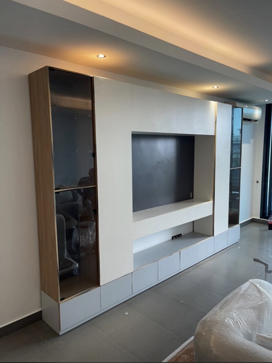 Meuble TV toute hauteur en MDF laqué blanc et chêne, avec vitrines fumées, réalisé par Babakaa à Douala